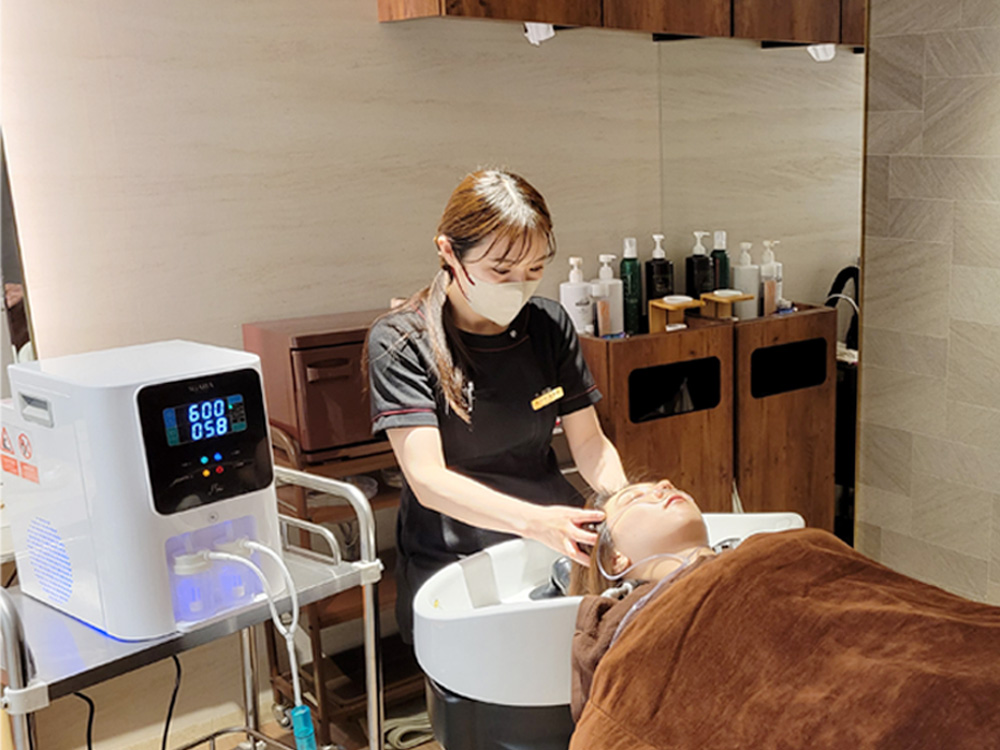 水素吸引しながらヘッドスパを受ける女性と担当スタッフ